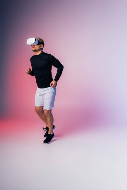 Мужчина в черной рубашке и белых шортах изящно двигается в студии, в виртуальной реальности - Фото, изображение