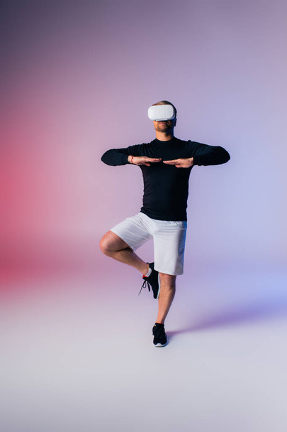 Ein Mann in schwarzem Hemd und weißen Shorts führt einen dynamischen Tanzschritt aus und zeigt Geschick und Leidenschaft in einem Studio-Setting. - Foto, Bild