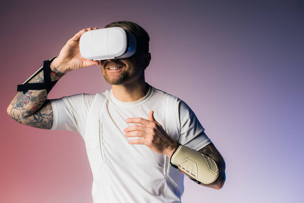 A man in a white shirt holds a white VR headset up to his face in a studio setting. - Photo, Image