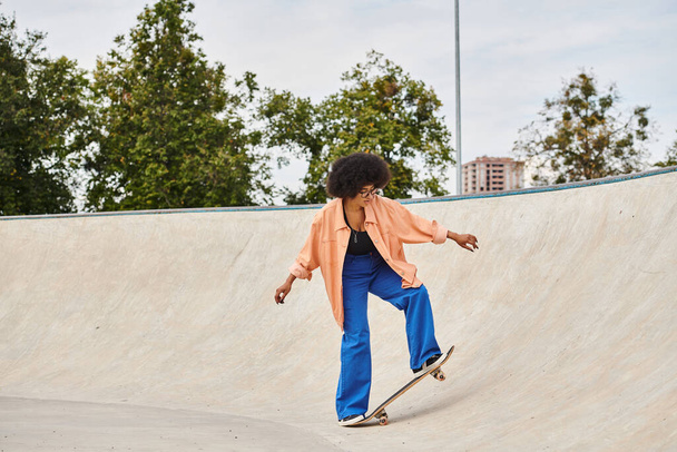 A young African American woman with curly hair boldly rides her skateboard up the side of a ramp at the skate park. - Photo, Image