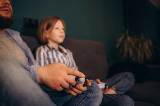 Excited by videogame victory little kid girl and her father raised hands scream with joy sit on sofa at home. Father his small daughter holds playing celebrate success feels happy.  - Photo, Image