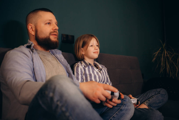 家族,ゲーム,エンターテイメントのコンセプト-幸せな父親と家庭でビデオゲームをプレイするゲームパッドを持つ小さな娘. 高品質の写真 - 写真・画像
