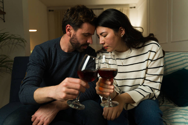 Розслаблена кавказька подружня пара має романтичну ніч побачень вдома під час пиття вина, яке відчувається в любовних емоціях - Фото, зображення