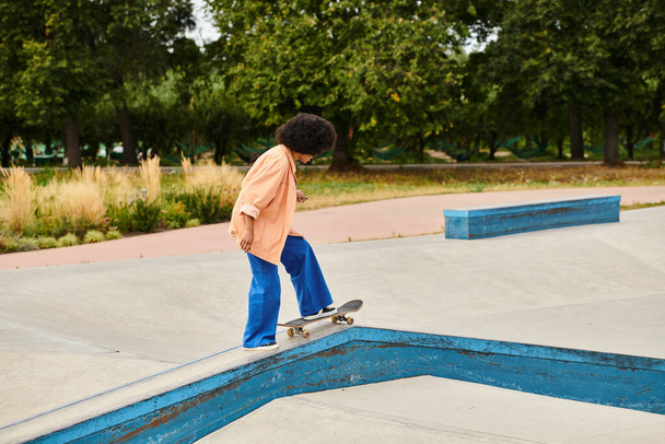 Young African American woman confidently rides his skateboard on a ramp with skill and determination. - Photo, Image