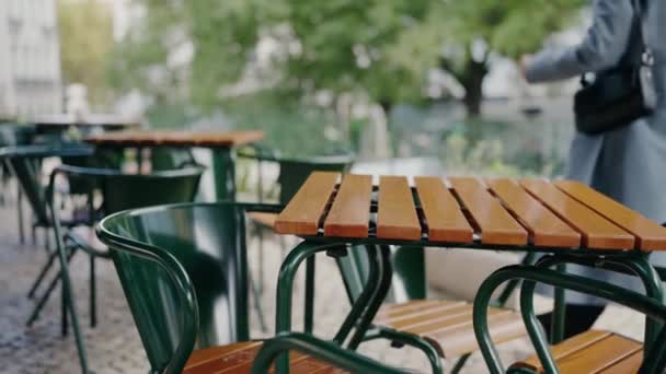Detailní informace o dřevěných stolech a židlích venkovní kavárny na městské ulici. Comfort restaurace nábytek venku a osoba procházející - Záběry, video