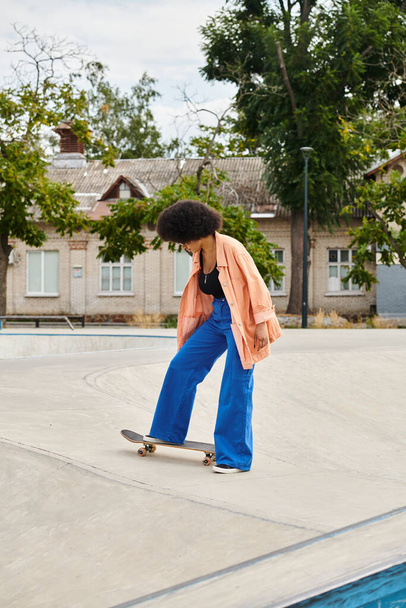 mujer negra hábilmente monta un monopatín en la parte superior de una rampa de cemento en un parque de skate al aire libre. - Foto, Imagen