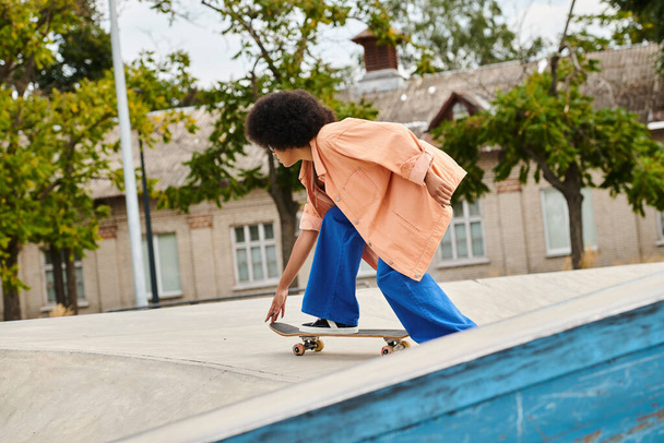 Young African American woman with curly hair skateboarding on a ramp at an outdoor skate park. - Photo, Image