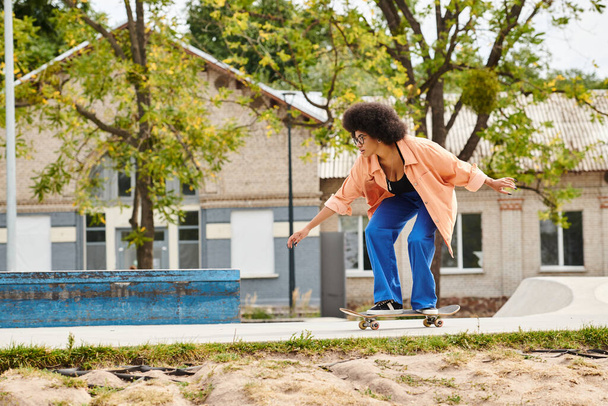 活気に満ちた都市環境の歩道でカーリーヘアスケートボードをしている若いアフリカ系アメリカ人女性. - 写真・画像