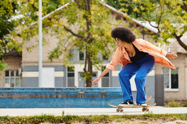 Une jeune Afro-Américaine avec une planche à roulettes fait du skateboard à côté d'une piscine dans un skate park urbain. - Photo, image