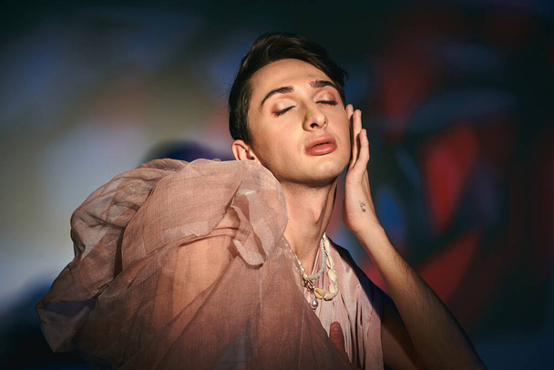 fashionista androgyne attrayante aux cheveux foncés dans une tenue élégante pastel posant les yeux fermés - Photo, image