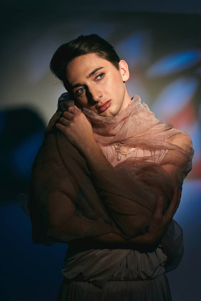 elegantní sofistikované androgynous muž v pastelové elegantní oblečení odvrací na pulzující pozadí - Fotografie, Obrázek