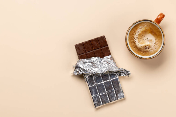 コーヒーブレイクブリス: チョコレートバーは,コーヒーのカップとペアリング. コピースペースとフラットレイ - 写真・画像