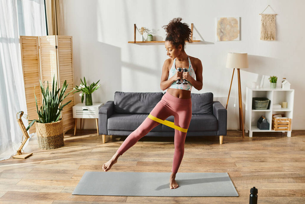 Afrikai amerikai nő aktív viselet gyakorló jóga egy hangulatos nappali környezetben. - Fotó, kép