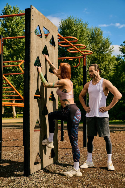 A woman in sportswear, guided by a personal trainer, climbing a rock wall, showcasing determination and motivation. - Photo, Image