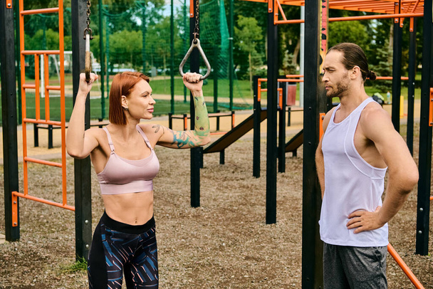 Мужчина и женщина в спортивной одежде стоят вместе в парке, демонстрируя решимость и мотивацию - Фото, изображение