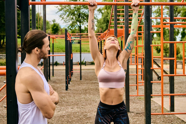 Muž a žena ve sportovním oblečení spolu cvičí pod jasnou oblohou před tělocvičnou. Osobní trenér ji motivuje. - Fotografie, Obrázek