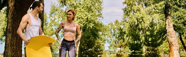 A man and a woman in sportswear stand in a park, energized and determined, working out together, personal trainer. - Photo, Image