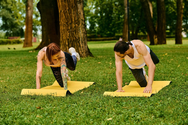 Um homem e uma mulher no sportswear envolvem-se no ioga do sócio poses com determinação e motivação durante uma sessão ao ar livre. - Foto, Imagem