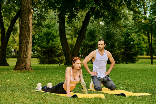 Una donna in abbigliamento sportivo pratica yoga posa in un parco lussureggiante guidato da un personal trainer, incarnando determinazione e motivazione. - Foto, immagini