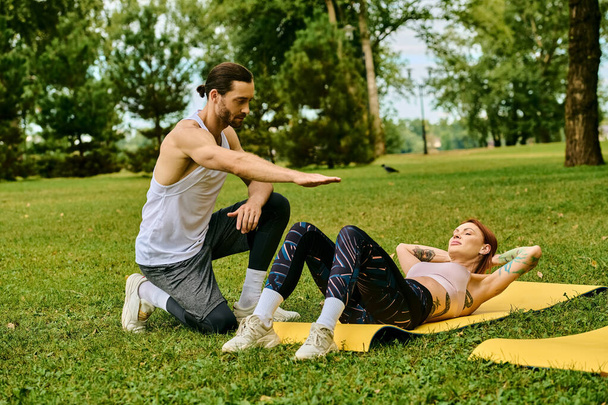A woman in sportswear exercising under the guidance of a personal trainer in a park, showcasing determination and motivation. - Photo, Image