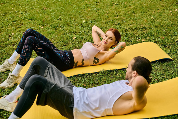 Un personal trainer guida una donna determinata in abbigliamento sportivo mentre esegue esercizi di yoga su stuoie all'aperto. - Foto, immagini