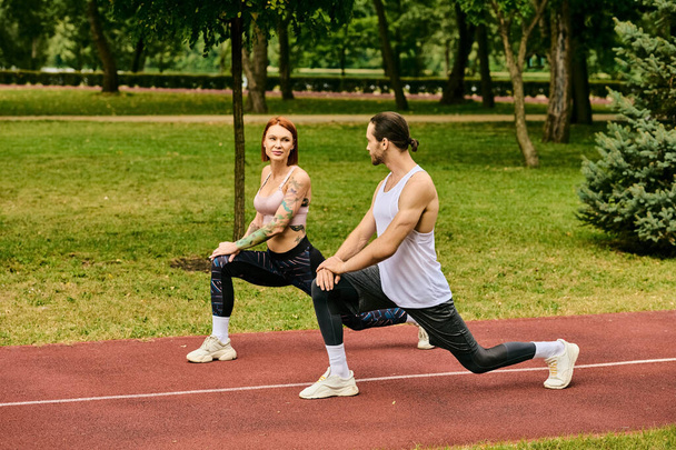 Een toegewijde vrouw in sportkleding beoefent sport met vastberadenheid begeleid door hun personal trainer in een rustige parkomgeving. - Foto, afbeelding