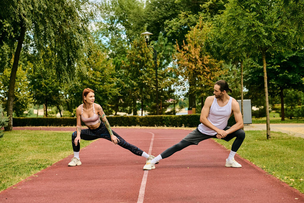 determinado hombre y mujer en ropa deportiva estiramiento, mostrando dedicación a su entrenamiento al aire libre. - Foto, Imagen