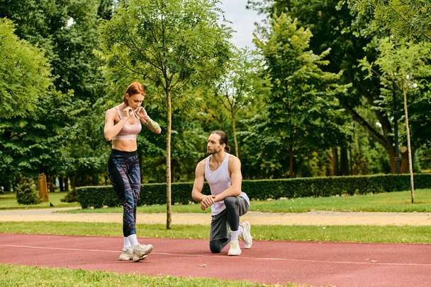 Ένας προσωπικός εκπαιδευτής καθοδηγεί μια γυναίκα σε αθλητικά είδη μέσω υπαίθριων ασκήσεων σε ένα παγκάκι του πάρκου, δείχνοντας αποφασιστικότητα και κίνητρο.. - Φωτογραφία, εικόνα