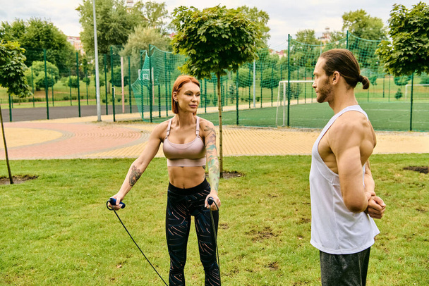 Kobieta w odzieży sportowej ćwiczy z trenerem personalnym w parku, wykazując determinację i motywację. - Zdjęcie, obraz