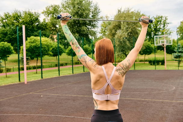 Een vastberaden vrouw in sportkleding met een springtouw in een park, die motivatie en kracht belichaamt. - Foto, afbeelding