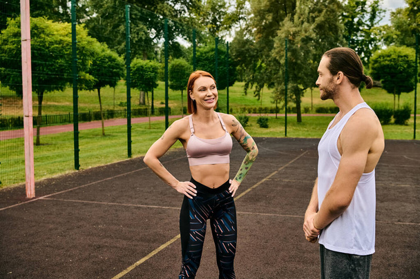 Een man en een vrouw in sportkleding staan klaar op een tennisbaan en tonen vastberadenheid en motivatie met hun personal trainer.. - Foto, afbeelding