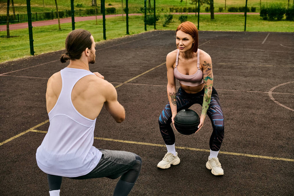 Чоловік і жінка в спортивному одязі тренуються з м'ячем, тренуючись особистим тренером на відкритому повітрі. - Фото, зображення