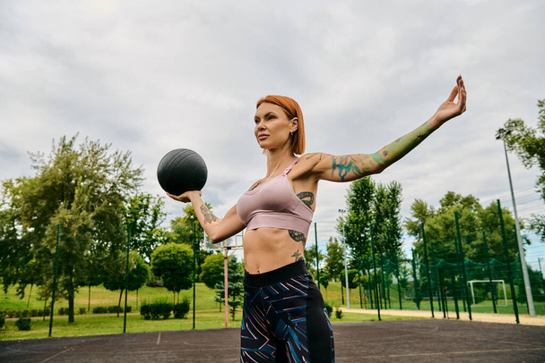 Μια αποφασισμένη γυναίκα στα αθλητικά κρατά με αυτοπεποίθηση μια μπάλα - Φωτογραφία, εικόνα