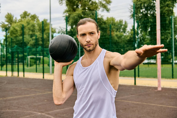 Un hombre sostiene una pelota en una mano y una pelota en la otra, mostrando determinación y enfoque en su rutina de ejercicios. - Foto, imagen