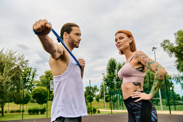 Una mujer en ropa deportiva, con un entrenador personal, que participa en ejercicios al aire libre con determinación y motivación. - Foto, imagen
