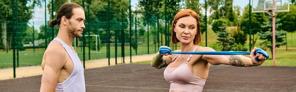 Μια γυναίκα σε αθλητικό ντύσιμο σταθεί σε ένα γήπεδο, ενώ η άσκηση με προσωπικό γυμναστή. - Φωτογραφία, εικόνα