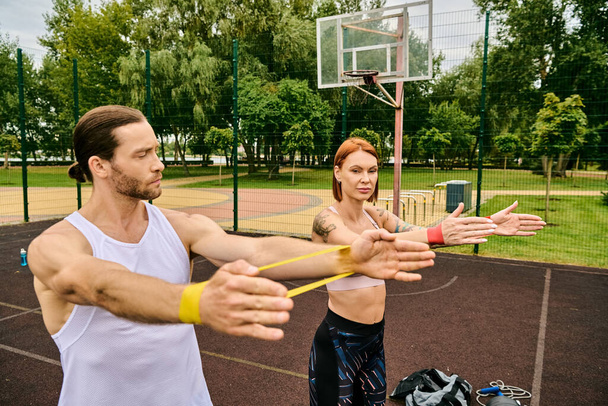 Um homem e uma mulher em sportswear tendo treinamento banda de resistência com determinação e motivação ao ar livre. - Foto, Imagem