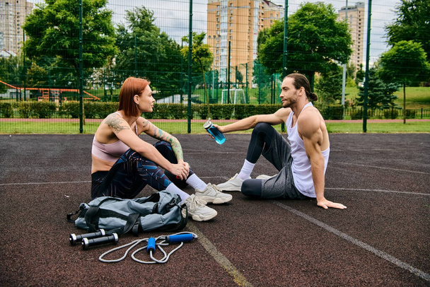 Ένας άνδρας και μια γυναίκα γυμνάζονται μαζί σε ένα γήπεδο μπάσκετ, επιδεικνύοντας αποφασιστικότητα και κίνητρο.. - Φωτογραφία, εικόνα