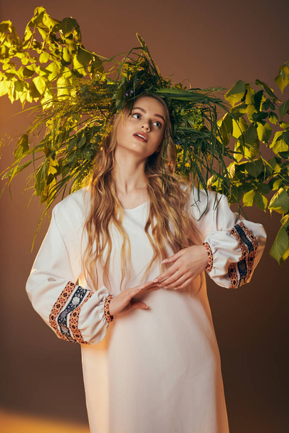Mladá žena, ozdobená tradičním oděvem, zdobí ateliér v ozdobných bílých šatech připomínajících vílu s rozevlátými dlouhými vlasy. - Fotografie, Obrázek