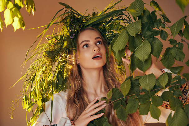 A young mavka in a traditional outfit stands gracefully in front of a lush green plant in a fairy and fantasy-themed studio setting. - Photo, Image