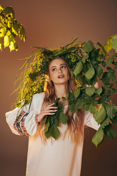 Νεαρή γυναίκα με παραδοσιακή ενδυμασία στολισμένη με ένα στεφάνι από φύλλα εμπνευσμένο από νεράιδα και φαντασία σε ένα σκηνικό στούντιο. - Φωτογραφία, εικόνα