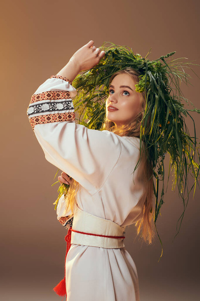 Μια νεαρή γυναίκα με παραδοσιακή ενδυμασία φοράει ένα περίτεχνο στεφάνι σε ένα στούντιο, που ενσωματώνει μυθικά και φανταστικά στοιχεία.. - Φωτογραφία, εικόνα