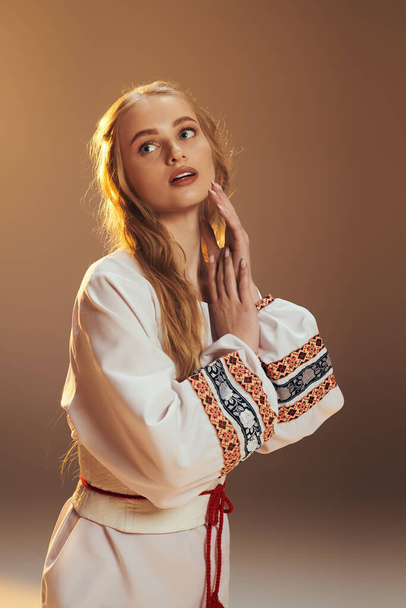 Une jeune femme en robe blanche tient gracieusement ses mains dans une pose sereine, incarnant un sentiment de paix et de beauté. - Photo, image