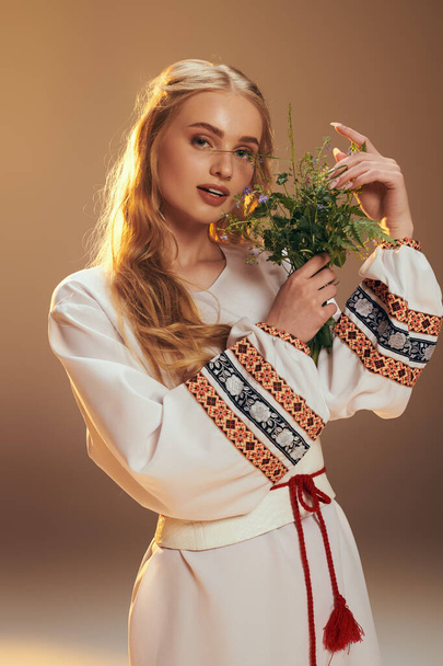 Eine junge Mavka in einem weißen Kleid hält zart eine Blume in einem märchenhaften und fantasievollen Studio-Setting. - Foto, Bild