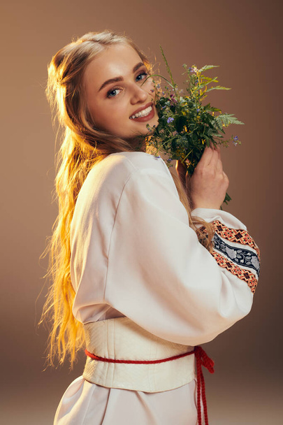 Ein junges Mädchen in einem weißen Kleid hält zart eine anmutige Blume in einem ruhigen Atelier-Ambiente. - Foto, Bild