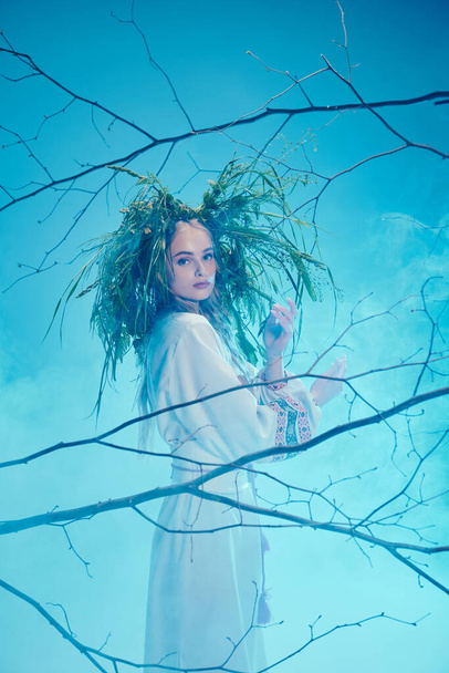 Een jonge mavka in traditionele feeënkleding staat vol vertrouwen in een boom, haar lange haar stroomt in de wind. - Foto, afbeelding