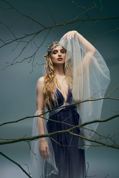 Een jonge vrouw met een etherische aanwezigheid draagt een mooie blauwe jurk en delicate sluier, die de essentie van een fantasie elf prinses belichaamt. - Foto, afbeelding
