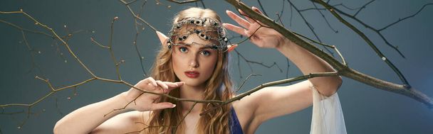 Uma jovem mulher em uma coroa fica graciosamente na frente de uma árvore majestosa em um cenário de fantasia, incorporando a essência de uma princesa elfo. - Foto, Imagem