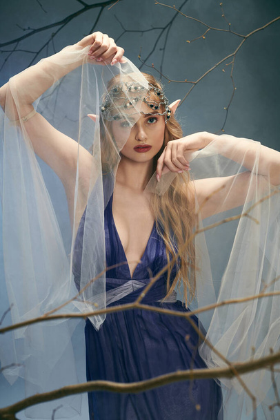 Mladá žena vyzařuje éterickou krásu v modrých šatech a závoj, ztělesňující podstatu pohádkové princezny ve studiu. - Fotografie, Obrázek
