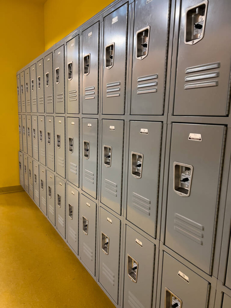 学校の廊下では,灰色のロッカーの均一な配列は,学生のための準備ができています, ベントとスムーズな金属製のドアをパンクするロック. - 写真・画像